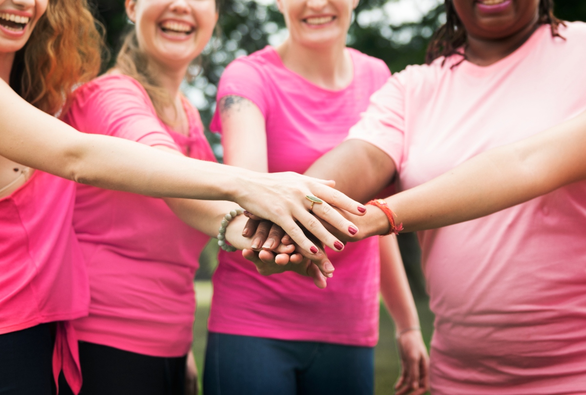 mujeres tomadas de la mano, mujeres sonriendo, mujeres vestidas de rosa, Mes del Cáncer, QuéOnnda